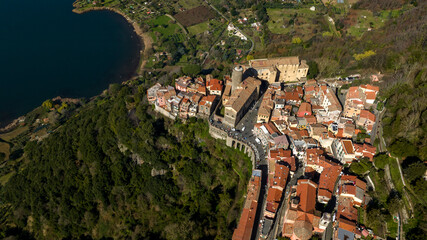 Aerial view of Nemi, a town of Castelli Romani regional park, in the Metropolitan City of Rome, Italy. The historic center is located in the Alban Hills overlooking Lake Nemi, a volcanic crater lake. 