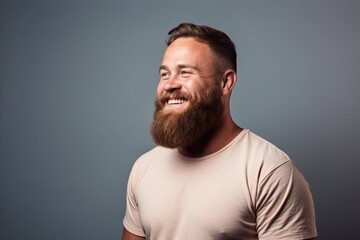 Portrait of a bearded hipster man looking up on grey background