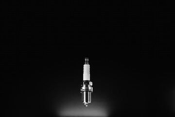 Spark plug isolated on black background. Spare part for a vehicle with an internal combustion engine, gasoline. A new detail. Car service concept. Copy space. Black and white