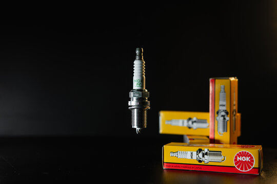 Khmelnytskyi, Ukraine - February 10 2024: Spark plugs for NGK gasoline engines. Set of Sparks with packaging on a black background. Auto parts sales concept. original box with spare parts. Copy space