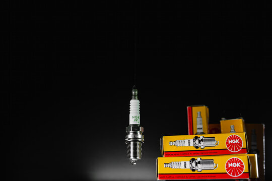Khmelnytskyi, Ukraine - February 10 2024: Spark plugs for NGK gasoline engines. Set of Sparks with packaging on a black background. Auto parts sales concept. original box with spare parts. Copy space