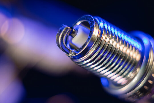 Close view. Automotive new spark plugs for gasoline engines. Nickel electrode, insulator. The concept of car service, repair. On a blue background.