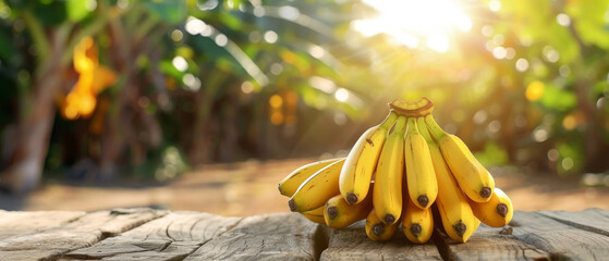 Ripe Bananas on Wooden Table in Tropical Setting, Ripe yellow bananas resting on a wooden table with a scenic backdrop of lush tropical greenery and banana trees.