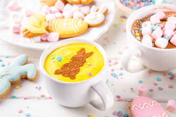 Hot sweet drinks for Easter party, breakfast, lunch. Easter menu. Pink, yellow, blue, brown multicolored hot chocolate cups with marshmallows, chocolate drawing rabbit, Easter eggs on latte surface