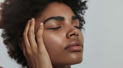 Naklejka premium A young woman with closed eyes her hands gently resting on her temples showcasing a serene and peaceful expression.