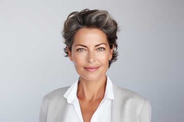 Fototapeta premium Portrait of a smiling businesswoman looking at camera over grey background