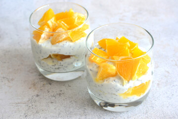 yoghurt, chia seeds and chopped orange in drinking glass close up
