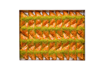 a tray of Turkish baklava sweets , triangular in shape, stuffed with cream and decorated with pistachios, isolated on a white background