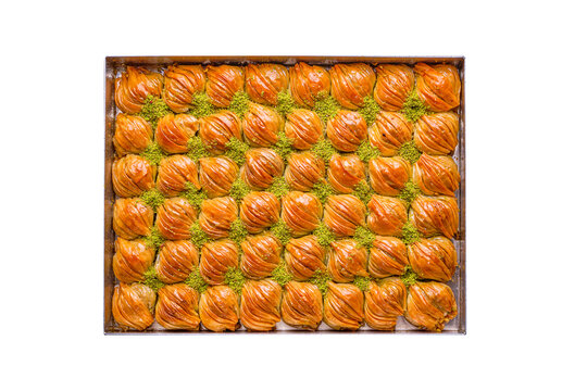 a tray of Turkish midye baklava sweets , decorated with pistachios, isolated on a white background