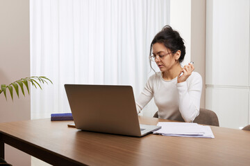 pretty woman in glasses using laptop and communicates with customer on internet at home