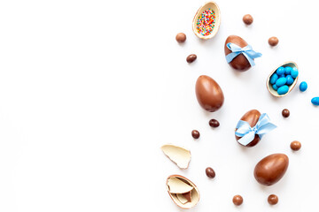 Happy Easter card. Chocolate Easter eggs in blue ribbon with sweets