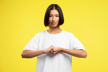 Smiling Asian woman wearing white t shirt, gesturing with fingers, showing connect gesture