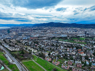 Aerial view from Hönggerberg over Swiss City of Zürich with lake and Swiss Alps in the background on a cloudy winter afternoon. Photo taken February 24th, 2024, Zurich, Switzerland.