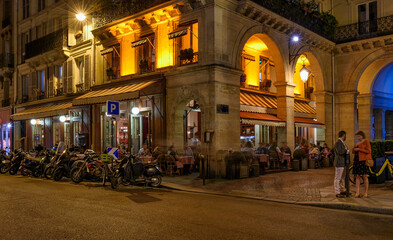 Cozy street with tables of cafe in Paris at night, France. Night cityscape of Paris. Architecture and landmarks of Paris. - 745823203