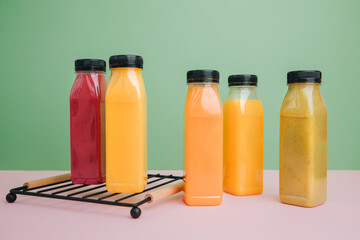 Fruit and vegetable smoothies in transparent plastic bottles. Green, red, orange smoothies on a pink-green background. The concept of healthy eating. Front view