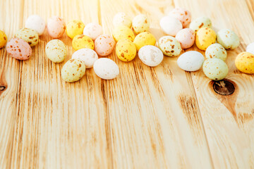 Multi-colored chocolate decorative eggs on a wooden background. Happy Easter background. Top view