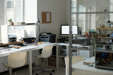 Part of spacious modern office with workplace of repairman of mobile gadgets with two chairs standing by desk with lamp and stationary
