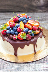Delicious cheesecake with melted chocolate, apples, strawberries, blueberries, peaches, raspberries and kumquats on the top, rustic background