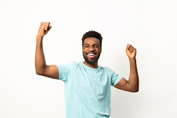 Portrait of a happy African American man smiling and raising his fists in victory or celebration against a white background. - 745841221