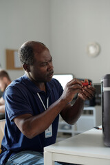 Mature African American specialist of technical repair center fixing parts of computer processor...