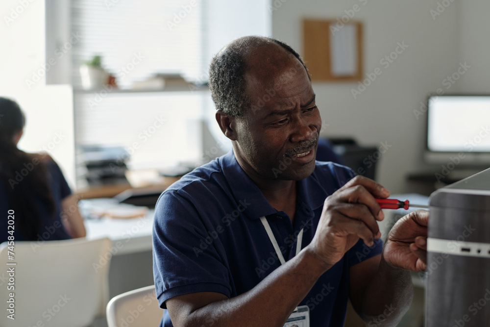 Poster mature male worker of technical repair center fixing parts of computer processor together with screw