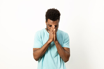 A man in casual attire shows signs of stress and exhaustion, holding his face in his hands against a white background. - 745842051