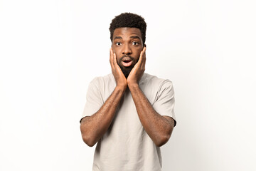 Portrait of a shocked young African American man holding his face in astonishment, isolated over a white background. - 745843401