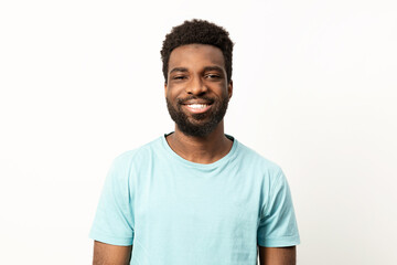Portrait of a happy young African American man with a bright smile, posing against a clean, plain background in a casual t-shirt. - 745847061
