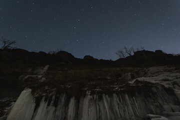 A cliff on the seashore in Paldiski in winter against the backdrop of the starry sky.