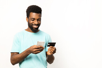 Afro American man shopping online with credit card and smartphone on a white background. Perfect for e-commerce, mobile payment, and technology concepts. - 745847858