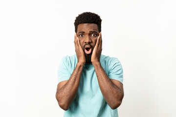 Surprised African American male in a blue t-shirt with a stunned expression against a clean, white backdrop. - 745848263
