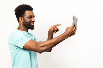 Smiling African American man confidently interacts with a digital tablet, isolated on a white background, exemplifying contemporary technology use and positive lifestyle. - 745849040