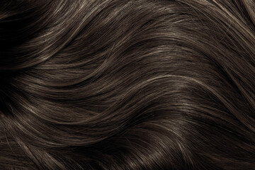 Brown hair close-up as a background. Women's long brown hair. Beautifully styled wavy shiny curls....