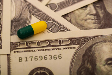 The juxtaposition of stacks of coins next to medical pills and capsules underscores the reality of...