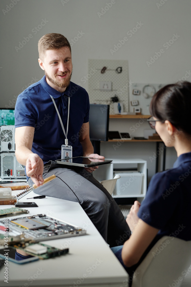 Aufkleber happy young technician of troubleshooting service using tablet and looking at female colleague while