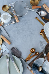 Various kitchen utensils are laid out in a circle on a gray concrete background. sieve, measuring spoons, knives, pizza cutter. space for text