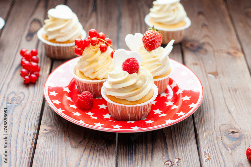 Wall mural vanilla cupcakes decorated with fresh strawberry, raspberry and red currant on rustic wooden backgro