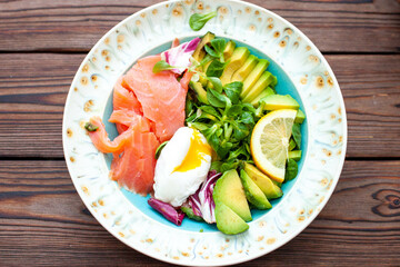 Brunch with poached egg, avocado, arugula, flax seeds and salted salmon on a rustic wooden background. flatlay, horizontal. copy space