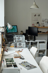 Disassembled laptop, electric handtool, broken smartphones and computer hardware on workplace of repairman in repair service center