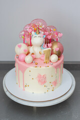 Cute birthday cake for a little girl with fondant unicorn, pink chocolate, lollipops, candies and...