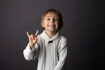 Cute little toddler boy, showing gesture in sign language on gray background, isolated image, child...