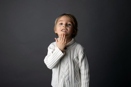 Cute little toddler boy, showing THANK YOU gesture in sign language on gray background, isolated image, child showing hand sings