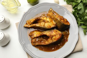 Tasty fish curry and ingredients on white marble table, flat lay. Indian cuisine