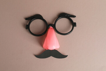 Funny mask with fake mustache, nose and glasses on grey background, top view