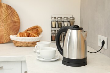 Electric kettle and cups on counter in kitchen