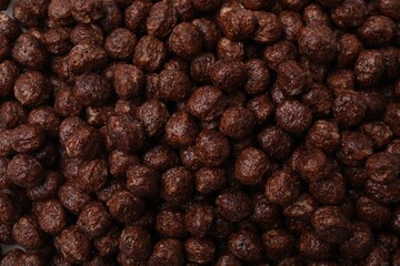 Tasty chocolate cereal balls as background, top view