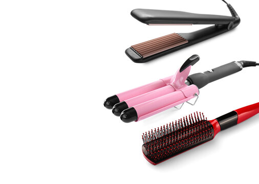 Hair irons and brush on white background