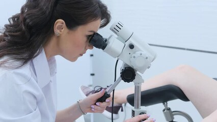 The patient and the doctor in the gynecological office during the colposcopy procedure. A gynecologist looks into a digital colposcopic microscope, studying women's diseases