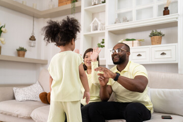 Happy African American family doing activities with daughter at home.