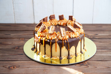 Gorgeous snickers cake with peanut butter cream, melted chocolate, candy bars and salted caramel